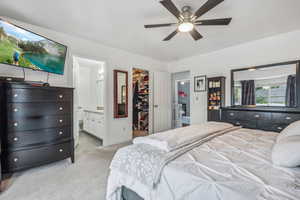 Carpeted bedroom with ceiling fan, a spacious closet, a closet, and ensuite bathroom