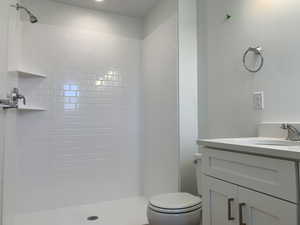 Bathroom featuring tiled shower, toilet, and vanity (photos are not of actual home this is a previously built home)