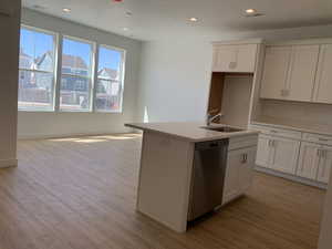 Kitchen with light hardwood / wood-style flooring, white cabinetry, stainless steel dishwasher, sink, and an island with sink (photos are not of actual home this is a previously built home)