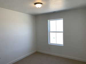 Carpeted empty room with plenty of natural light and a textured ceiling (photos are not of actual home this is a previously built home)