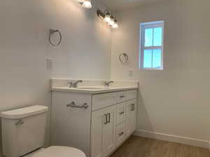 Bathroom with toilet, vanity, and wood-type flooring (photos are not of actual home this is a previously built home)