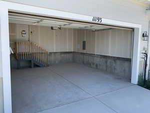 Garage featuring a garage door opener and electric panel (photos are not of actual home this is a previously built home)