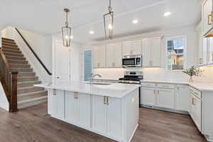 Kitchen with appliances with stainless steel finishes, dark hardwood / wood-style flooring, a kitchen island with sink, and sink