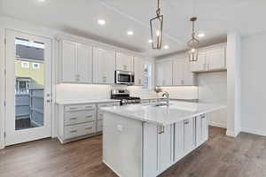 Kitchen with a kitchen island with sink, sink, appliances with stainless steel finishes, dark hardwood / wood-style flooring, and white cabinetry