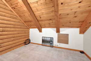 Additional living space with wood ceiling, lofted ceiling with beams, rustic walls, and light colored carpet