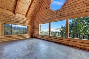 Unfurnished sunroom featuring a mountain view, lofted ceiling with skylight, wooden ceiling, and a wealth of natural light