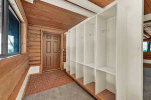 Mudroom featuring log walls and wood ceiling