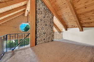 Additional living space with beam ceiling, carpet floors, rustic walls, and wood ceiling