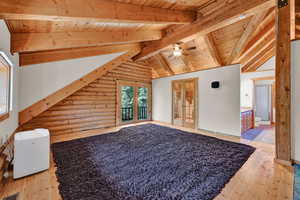 Additional living space with wooden ceiling, vaulted ceiling with beams, light hardwood / wood-style flooring, and rustic walls