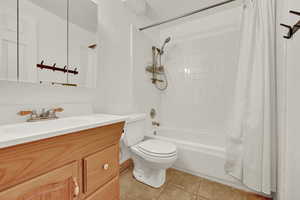 Full bathroom featuring toilet, vanity, shower / bath combo with shower curtain, and tile patterned floors