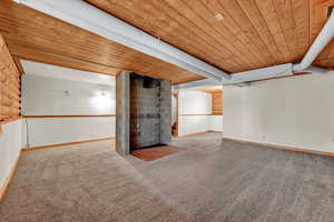 Basement with carpet floors, brick wall, and wood ceiling