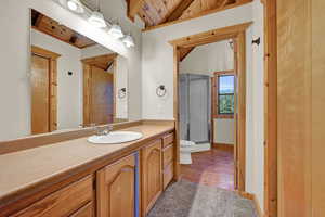 Bathroom featuring vaulted ceiling with beams, toilet, vanity, wood-type flooring, and wooden ceiling