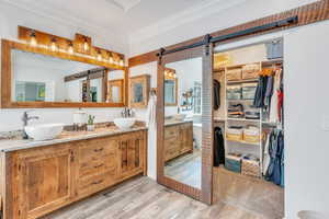 Primary bathroom with walk in closet, double vanity, and mirrored barn door