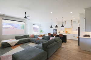 Living room featuring light hardwood / wood-style floors, ceiling fan, and a textured ceiling