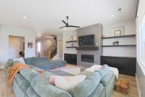 Living room featuring ceiling fan, a tiled fireplace, and light hardwood / wood-style floors