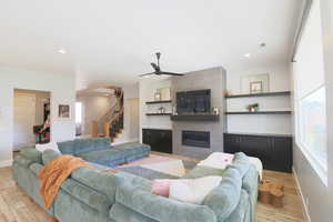 Living room featuring a tile fireplace, light hardwood / wood-style floors, ceiling fan, and plenty of natural light