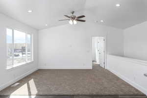 Spare room with vaulted ceiling, carpet floors, and ceiling fan