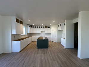 Kitchen with a kitchen island, wood-type flooring, and white cabinetry