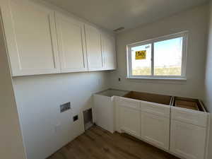 Laundry area with hardwood / wood-style flooring, hookup for a washing machine, cabinets, and hookup for an electric dryer