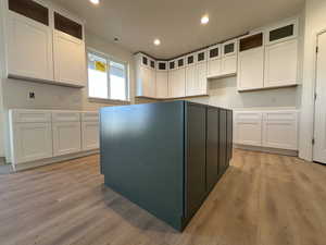 Kitchen with white cabinets, a center island, and light hardwood / wood-style floors