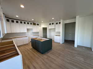 Kitchen with white cabinets, a kitchen island, and hardwood / wood-style flooring