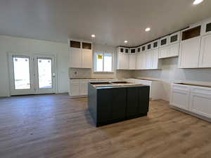 Kitchen featuring a kitchen island, light wood-type flooring, white cabinetry, and a wealth of natural light