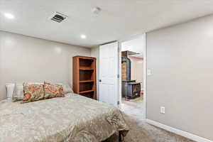 Downstairs guest bedroom with a textured ceiling and a wood stove