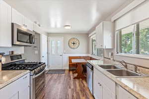 Kitchen with sink, stainless steel appliances, dark wood-type flooring, and white cabinets