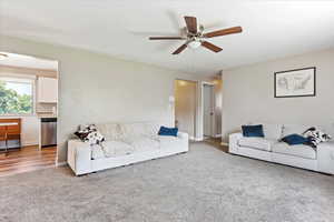 Carpeted living room featuring ceiling fan