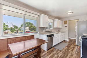 Kitchen with sink, dark hardwood / wood-style flooring, range, dishwasher, and white cabinets