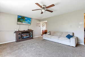 Carpeted living room featuring ceiling fan