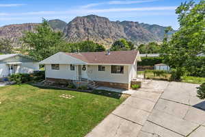 Ranch-style house featuring a storage unit, a front lawn, and a mountain view