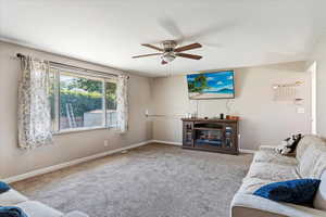 Carpeted living room featuring ceiling fan