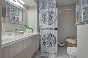 Bathroom featuring toilet, vanity, and tile patterned floors