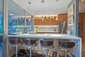 Kitchen with a breakfast bar, appliances with stainless steel finishes, kitchen peninsula, and decorative backsplash