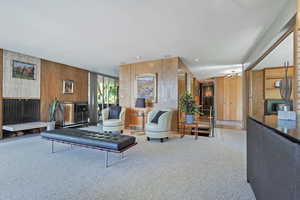 Carpeted living room with wood walls