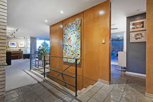 Corridor featuring track lighting and dark tile patterned floors