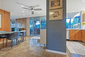 Tiled dining room with ceiling fan, sink, and floor to ceiling windows