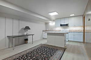 Kitchen featuring white cabinetry, sink, white range with electric stovetop, light wood-type flooring, and light stone countertops