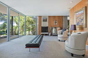 Carpeted living room with wood walls and expansive windows