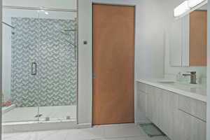 Bathroom featuring walk in shower, tile patterned flooring, and vanity