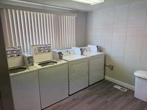 Clothes washing area featuring tile walls, washer and clothes dryer, and hardwood / wood-style flooring