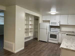 Kitchen featuring white cabinetry, sink, dark hardwood / wood-style flooring, and white appliances