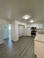 Kitchen featuring stainless steel appliances, decorative backsplash, white cabinetry, sink, and dark hardwood / wood-style flooring