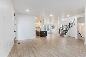 Unfurnished living room with a chandelier, light hardwood / wood-style floors, and sink