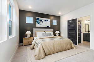 Bedroom featuring connected bathroom and light colored carpet