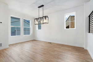 Unfurnished dining area with a chandelier and light wood-type flooring