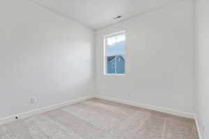 Empty room featuring light colored carpet