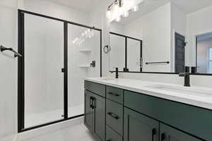 Bathroom with tile patterned flooring, vanity, and a shower with door