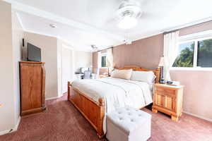 Carpeted bedroom with beam ceiling and multiple windows